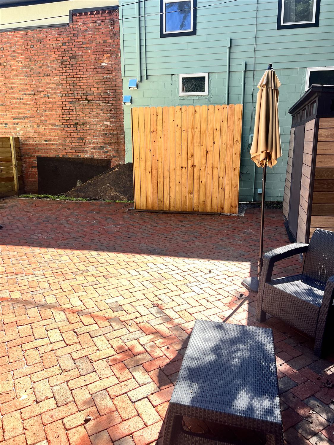 New wood fence panel on a brick courtyard between two buildings