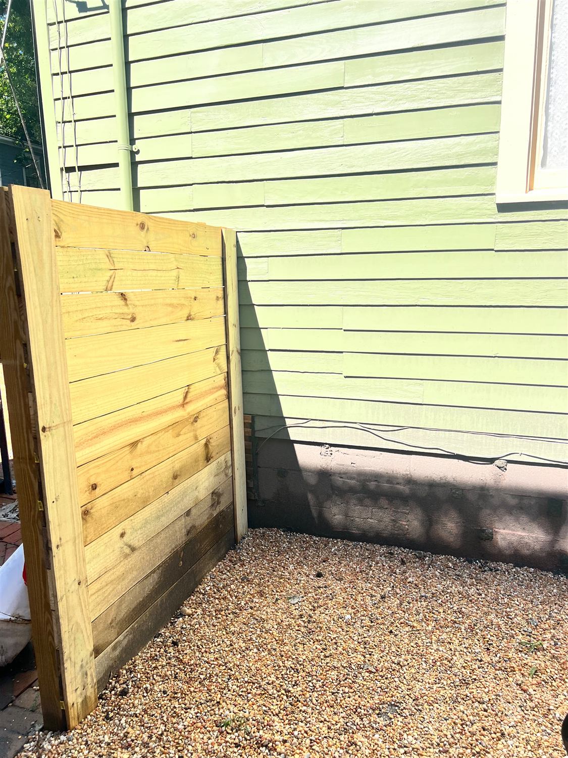 New horizontal wood privacy screen set over a pea gravel bed
