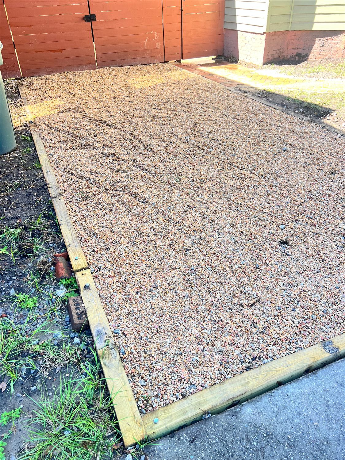 Timber-bordered pea gravel pad meeting the street apron