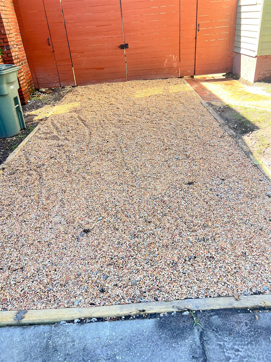 Pea gravel parking pad with a timber border in front of wood gates in Savannah