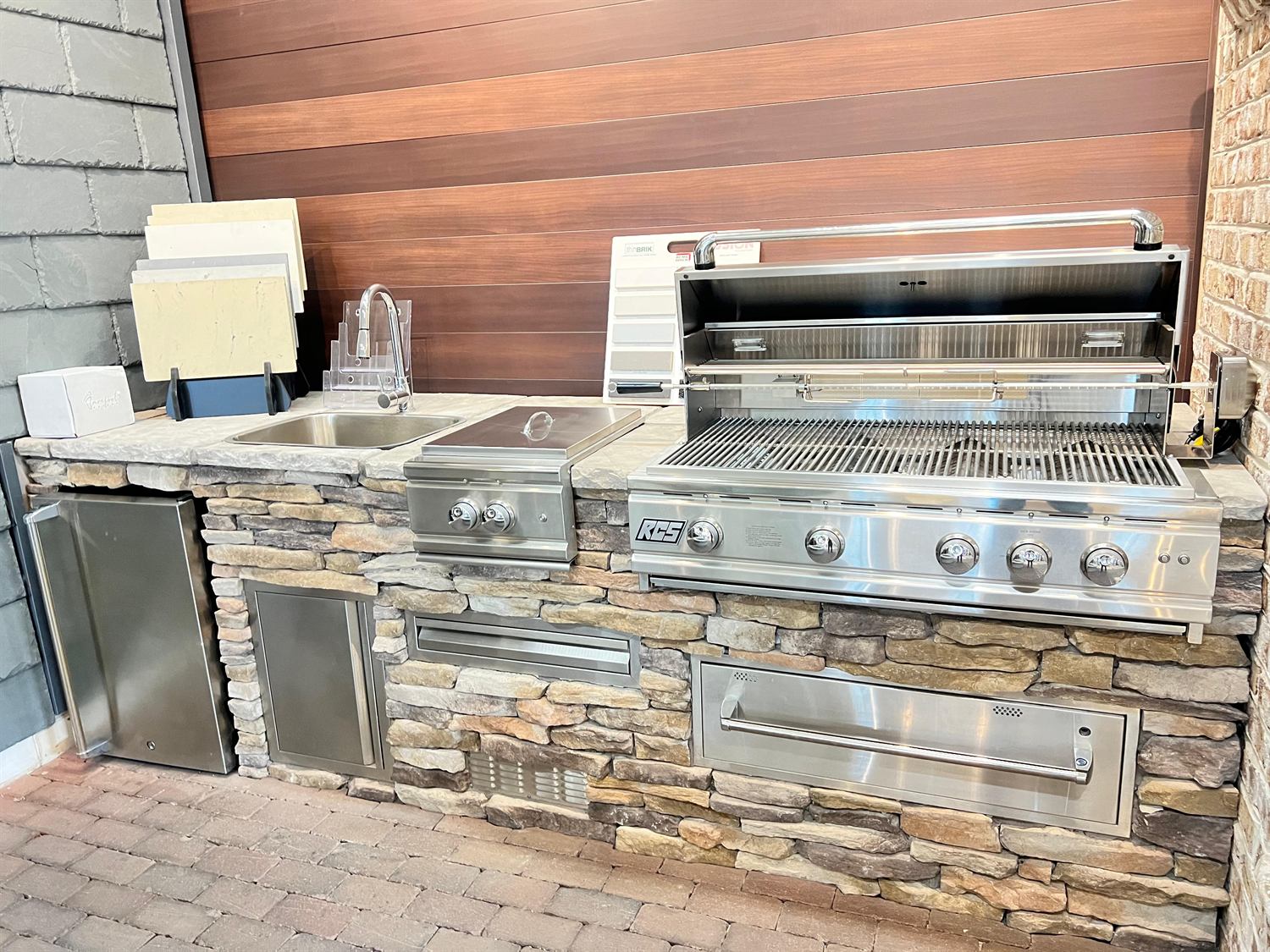 Outdoor kitchen in stacked stone with a sink, side burner and grill, built by Lalo's Home Improvements