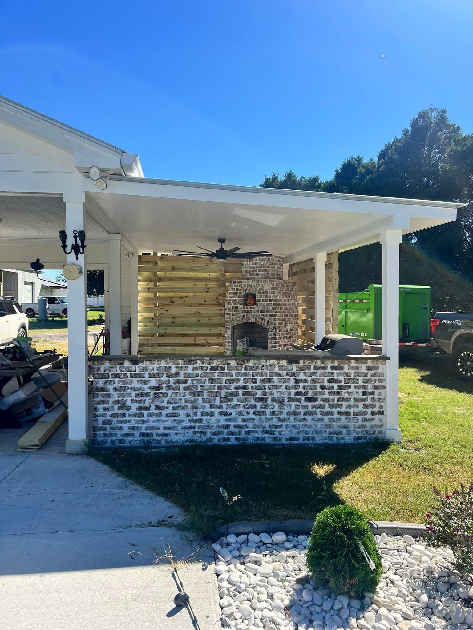 Covered outdoor kitchen and fireplace seen from the yard