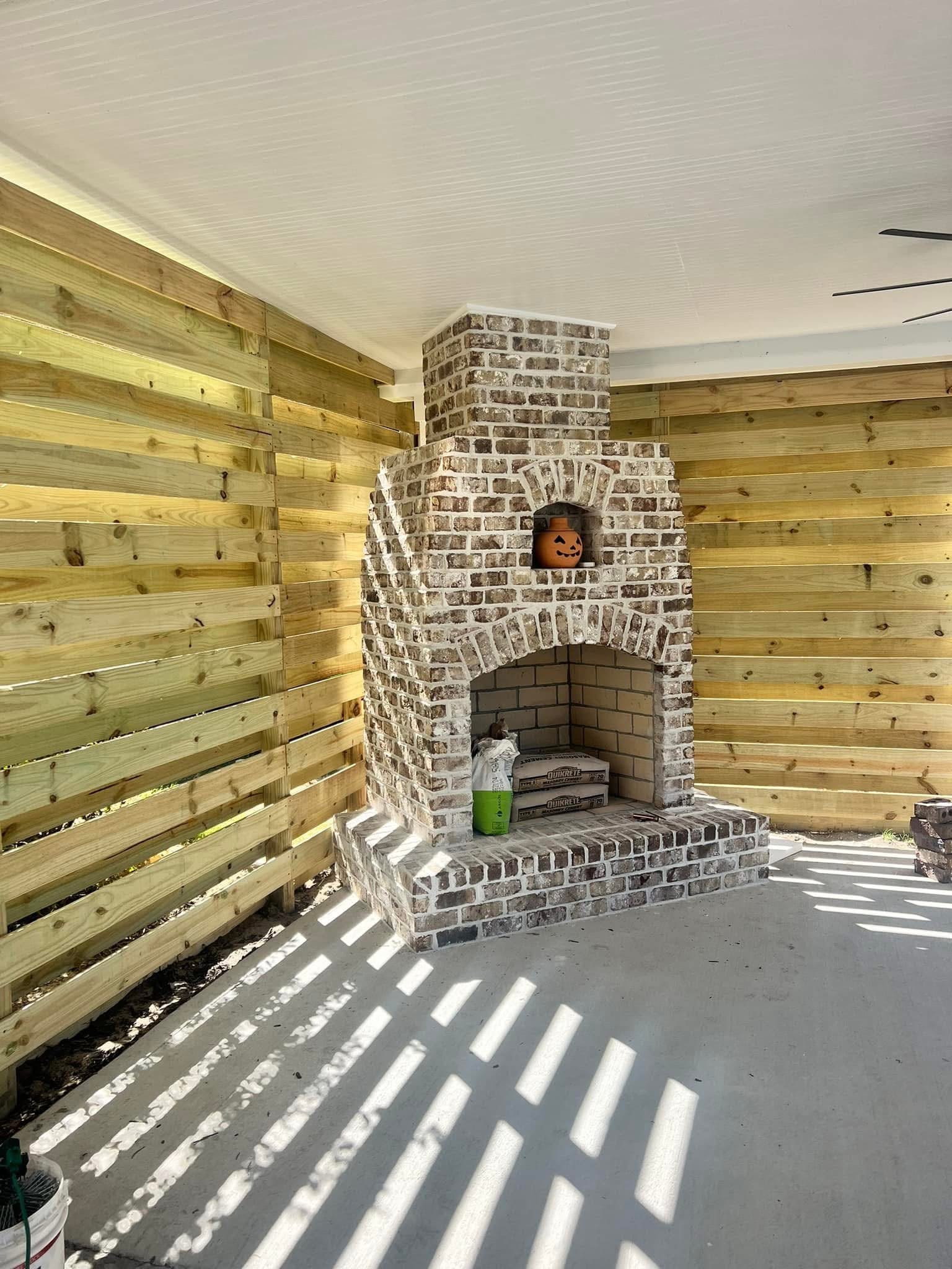 Brick outdoor fireplace with a horizontal wood privacy screen