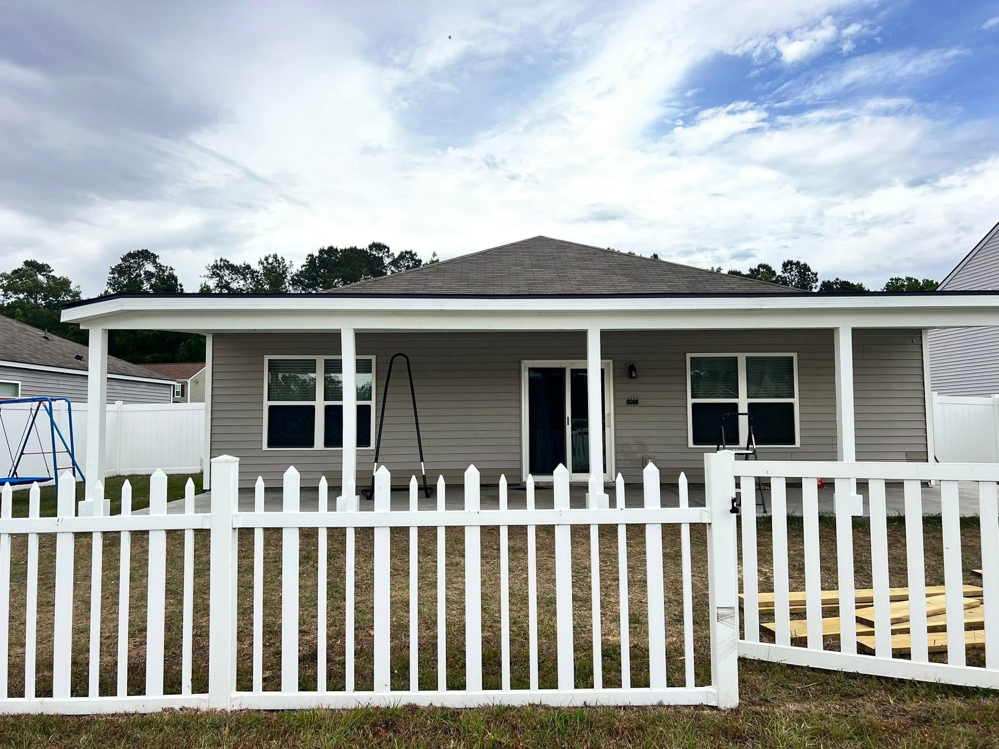 Rear covered patio spanning the back of a home behind a white picket fence