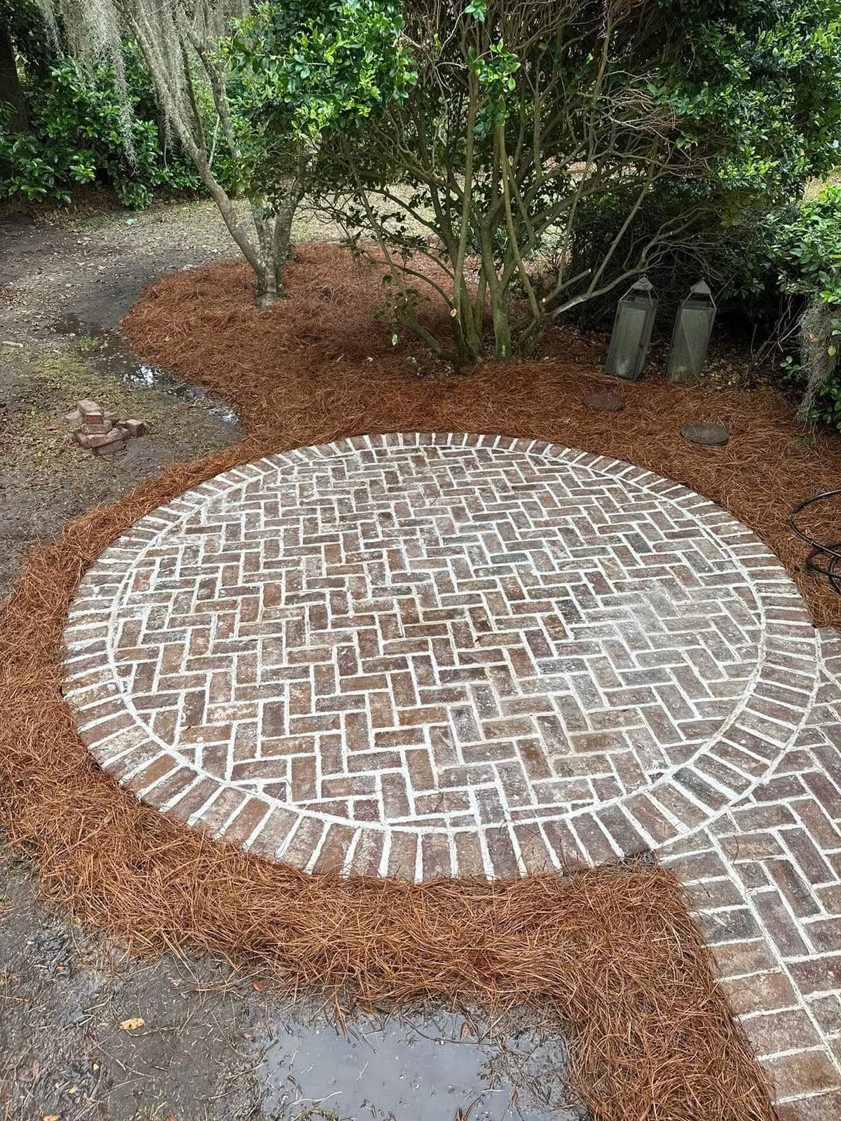 Finished circular brick patio surrounded by pine straw beds