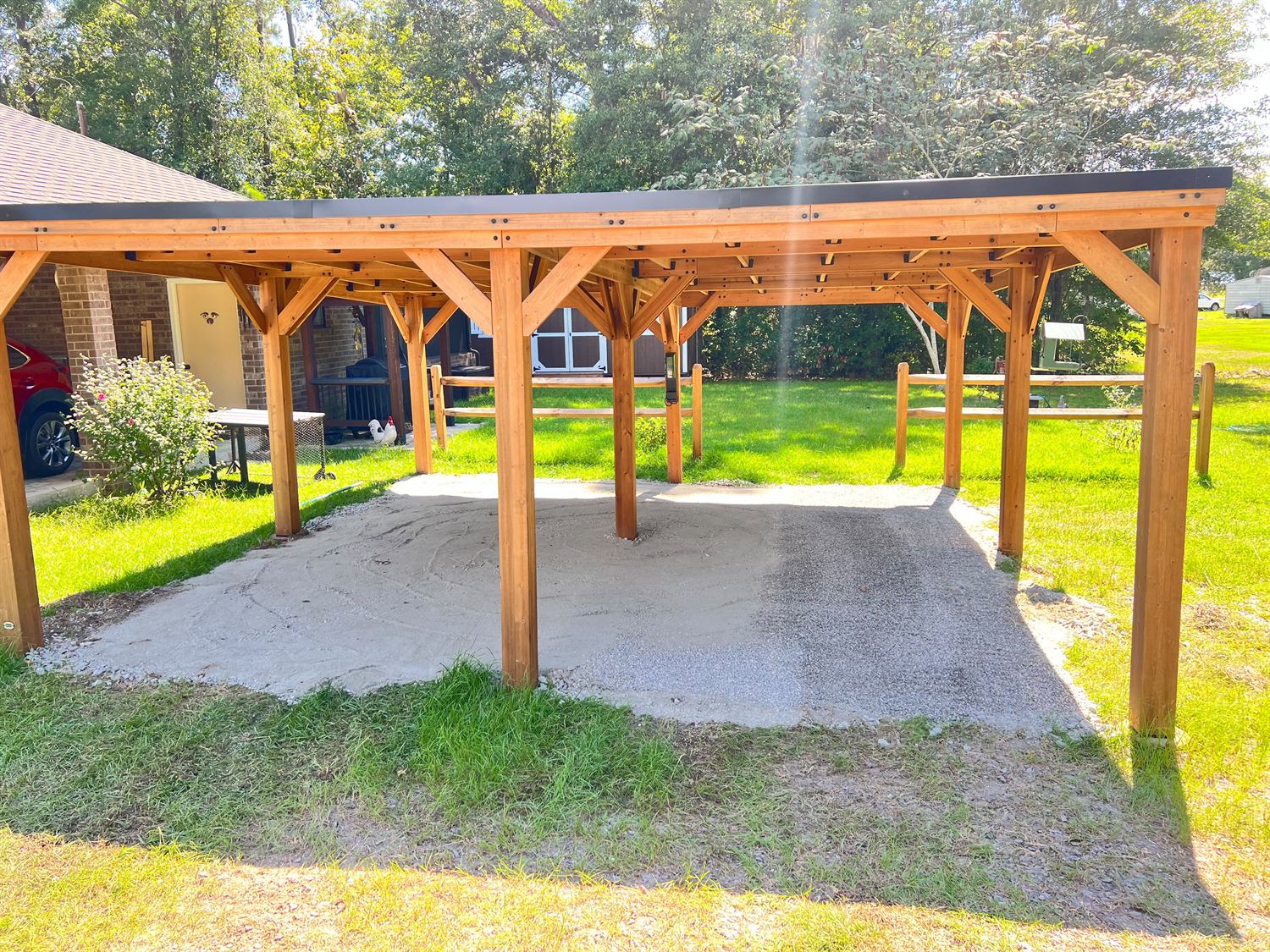 Free-standing cedar pavilion with a black standing-seam roof over a gravel pad