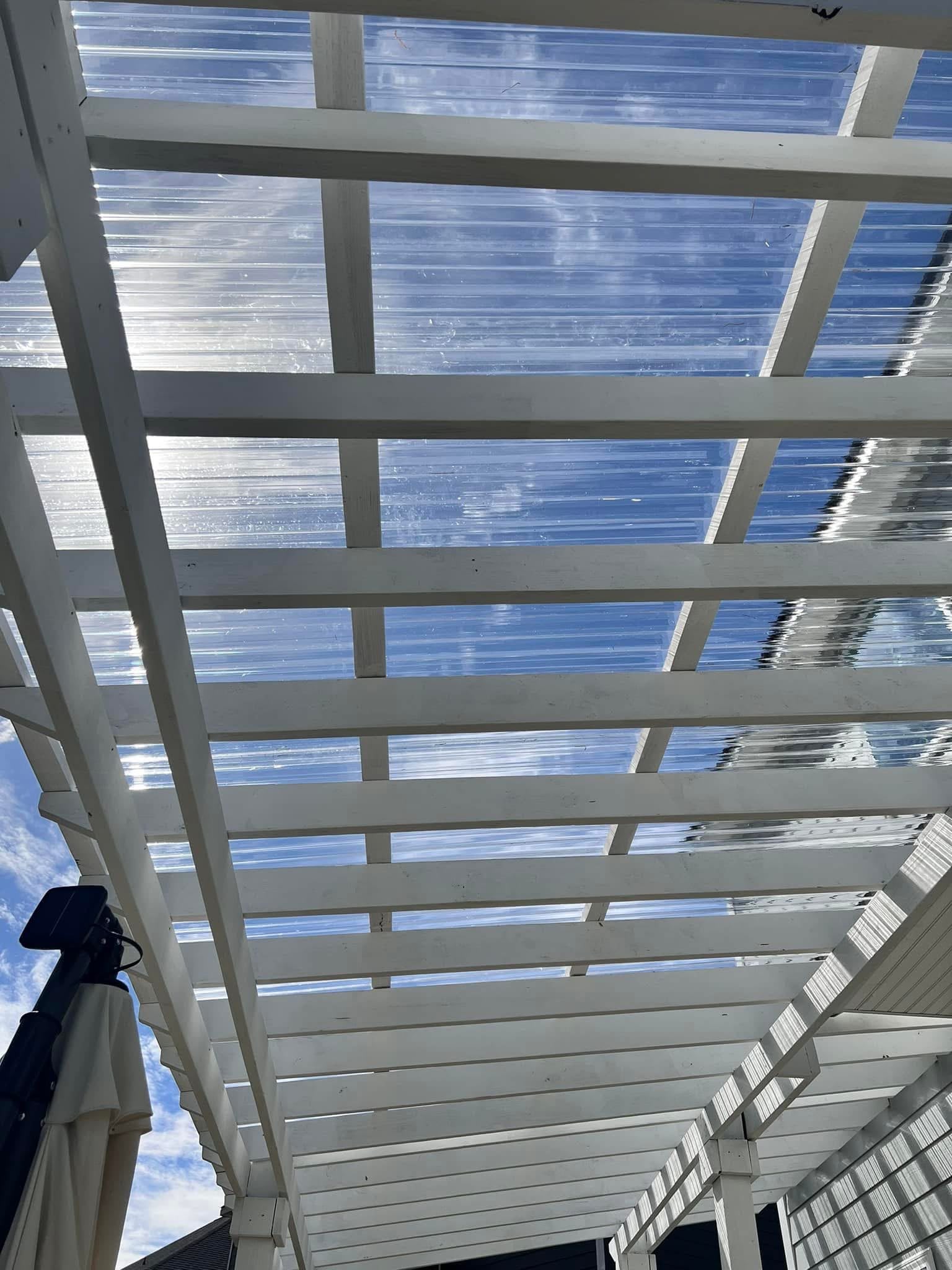 White pergola with clear polycarbonate roof panels seen from below
