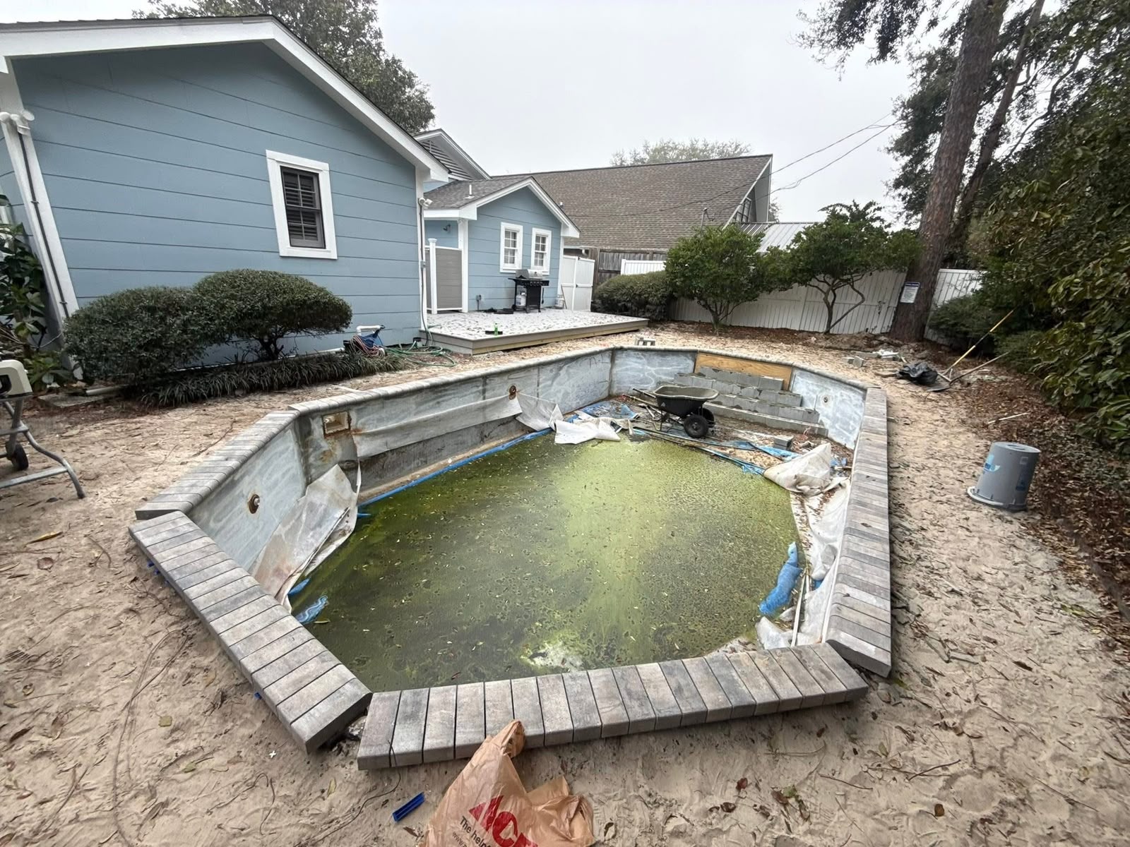 Old in-ground pool with paver coping being drained and removed