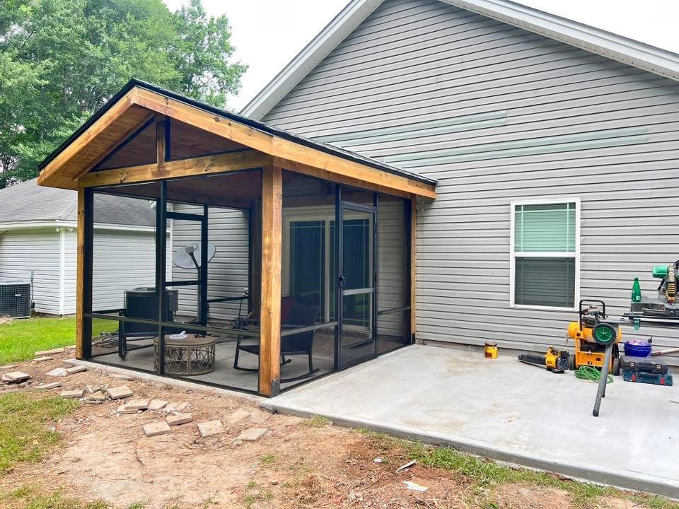 Cedar screened porch with a gable roof beside a concrete patio