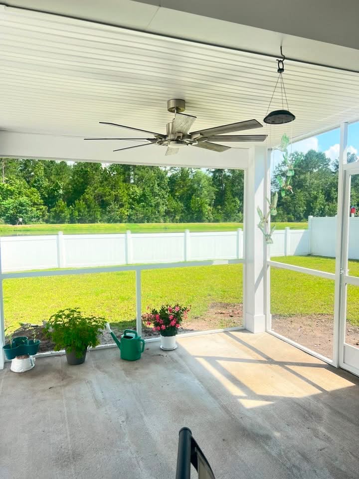 Screened porch interior with a ceiling fan overlooking a pond