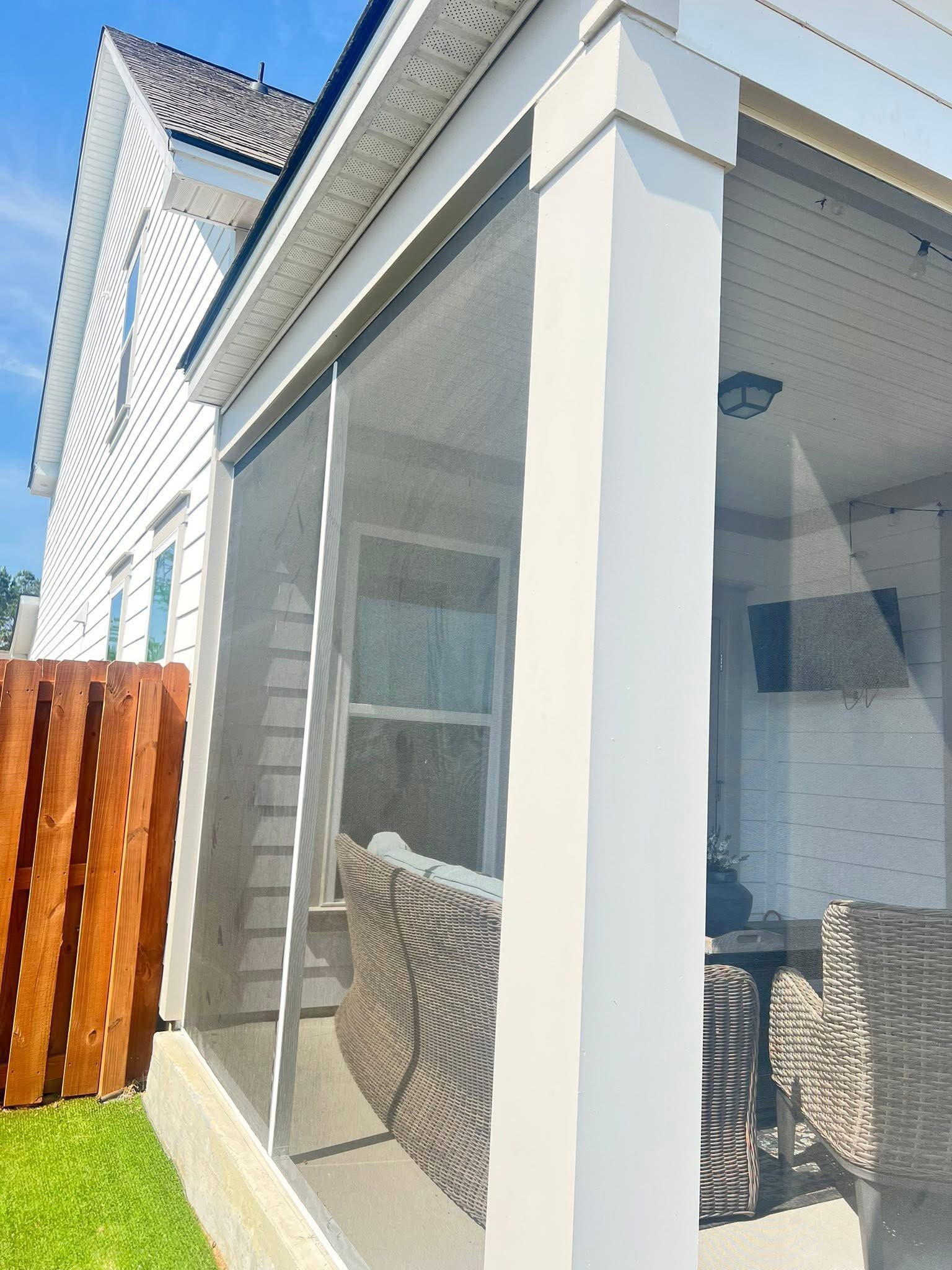 Side view of a white screened porch beside a fence