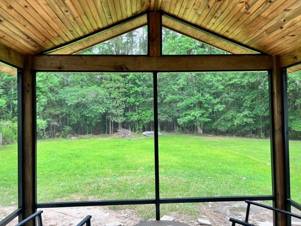 Inside a screened porch with a cedar ceiling looking out over the woods