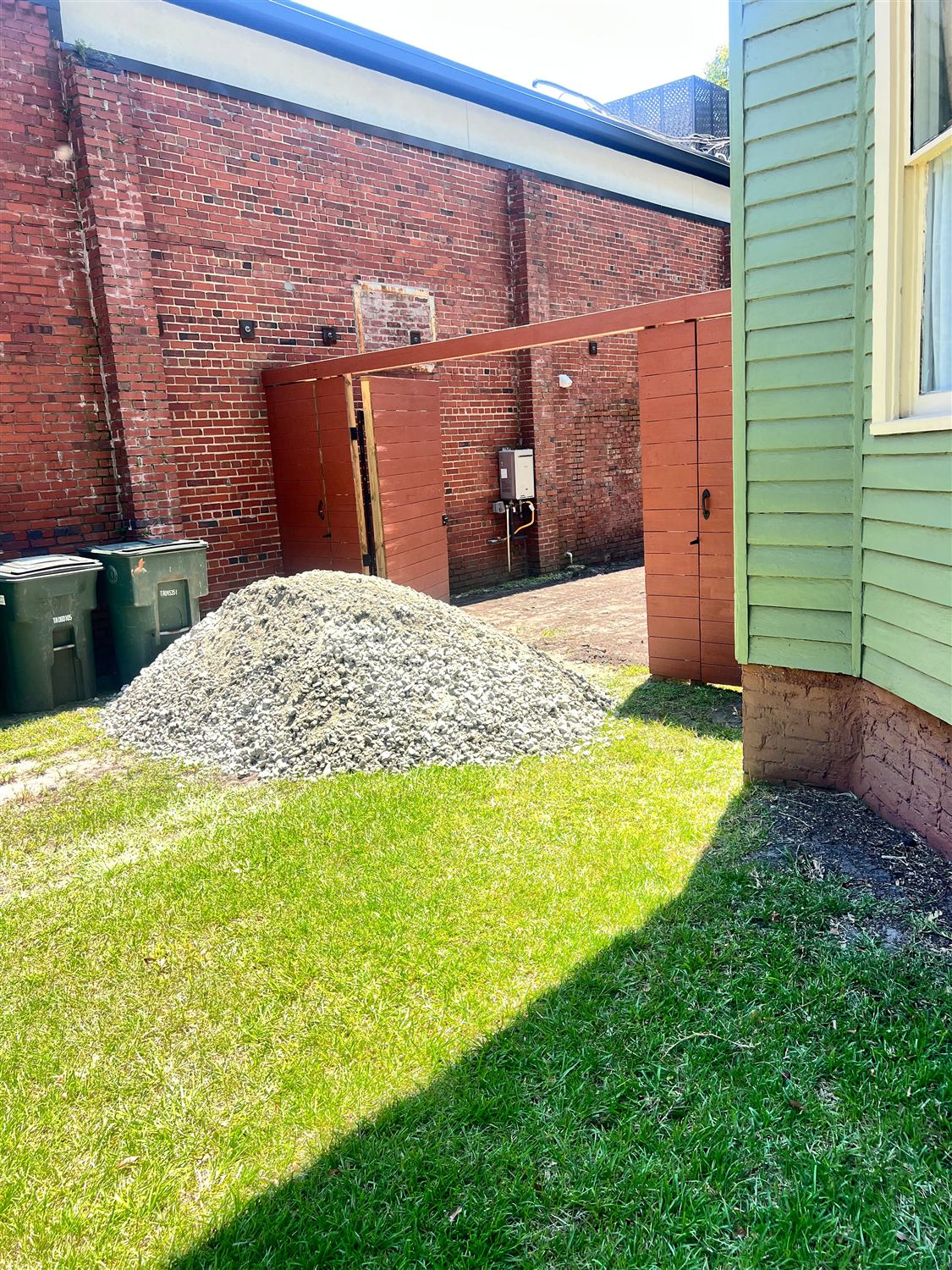 Gravel delivered on the lawn beside a new wood gate